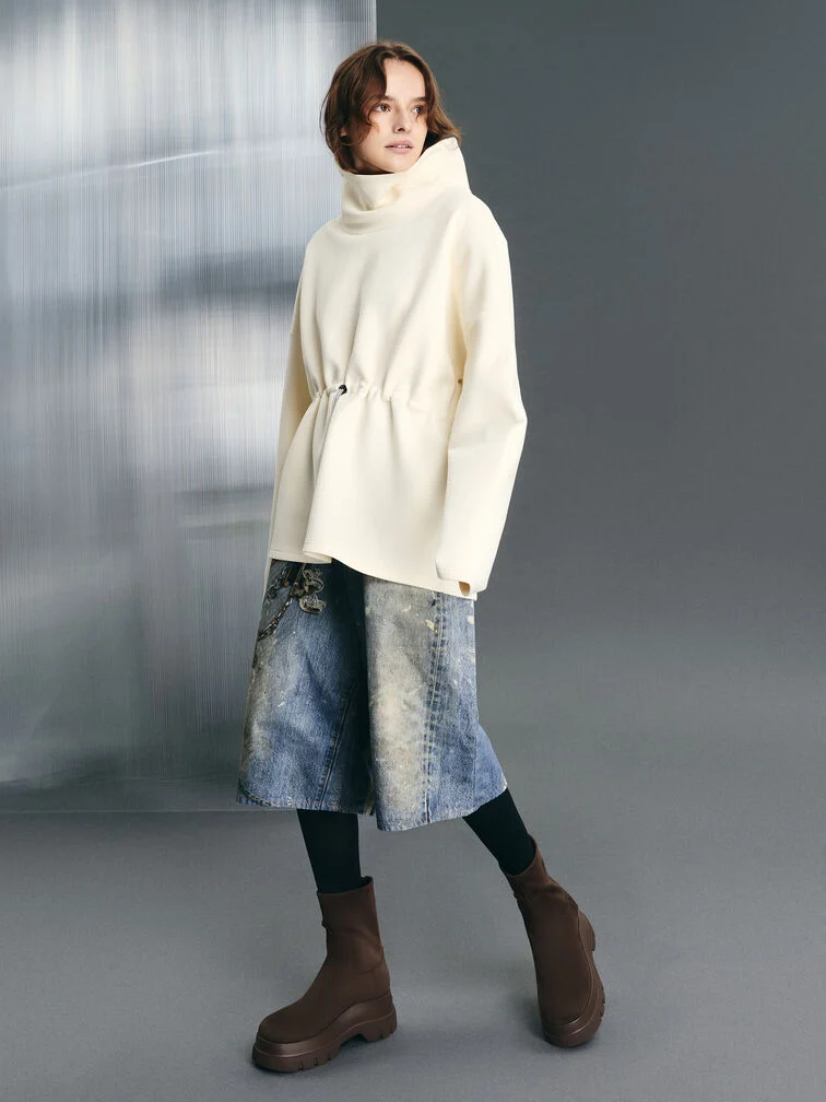 Dark brown chunky ankle boots anchor an oversized white top and light-wash jorts combination.