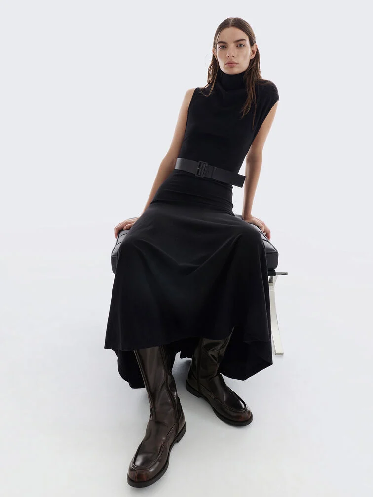 A long belted black dress styled with knee-high loafer boots.
