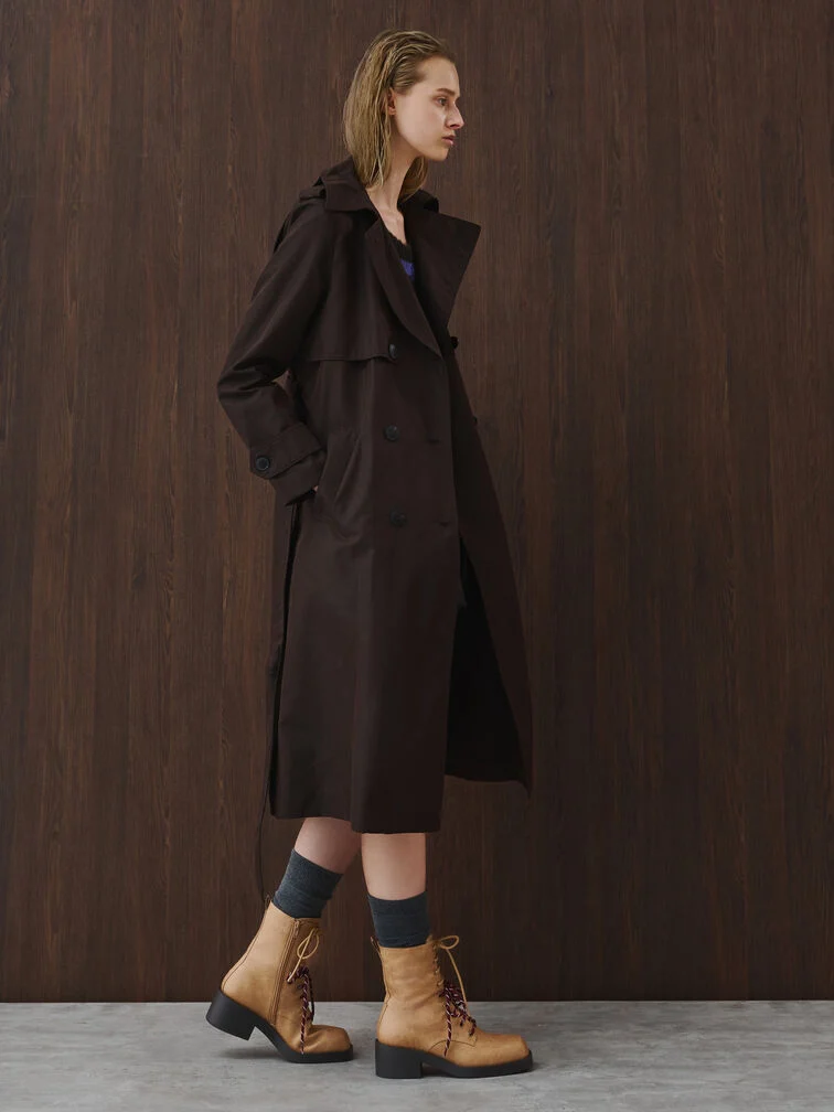 A layered ensemble styled with a trench coat and ankle boots.