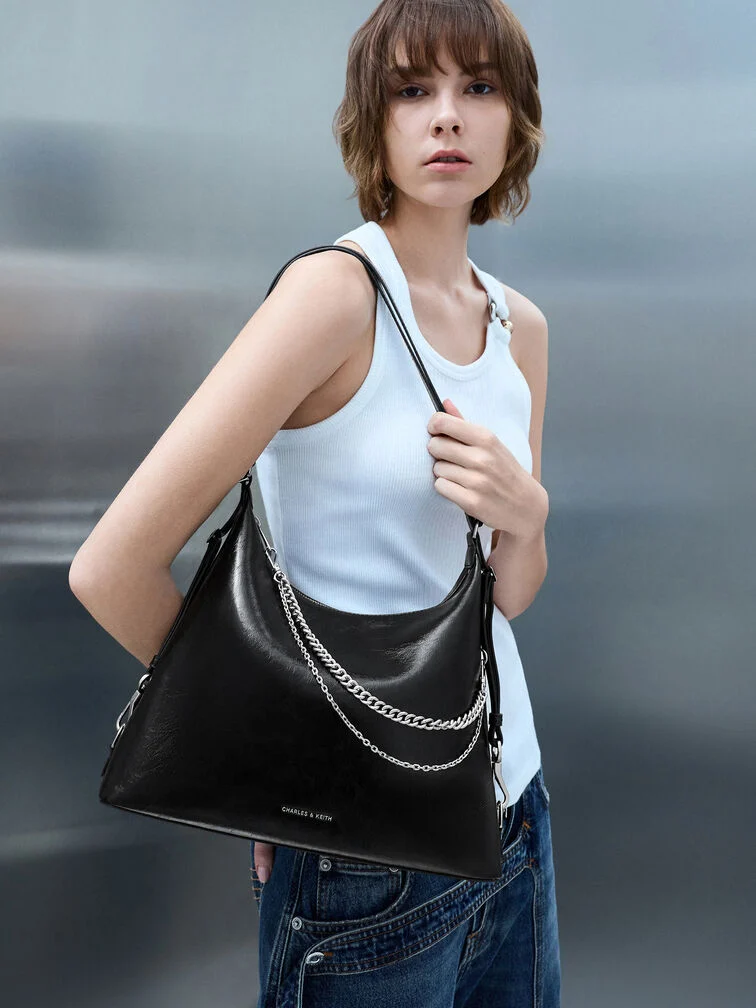 Black hobo bag with a hanging chain detail, adding an edgy touch to everyday wear.