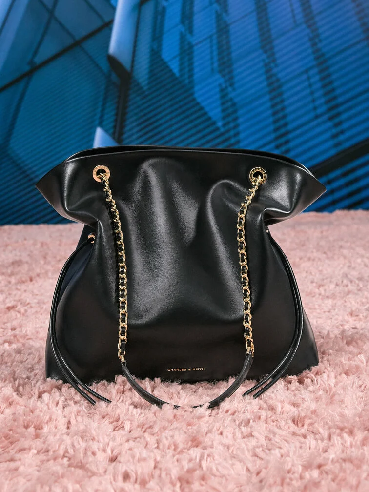Slouchy tote bag with drawstring detailing and braided chain straps, ideal for day-to-night wear.