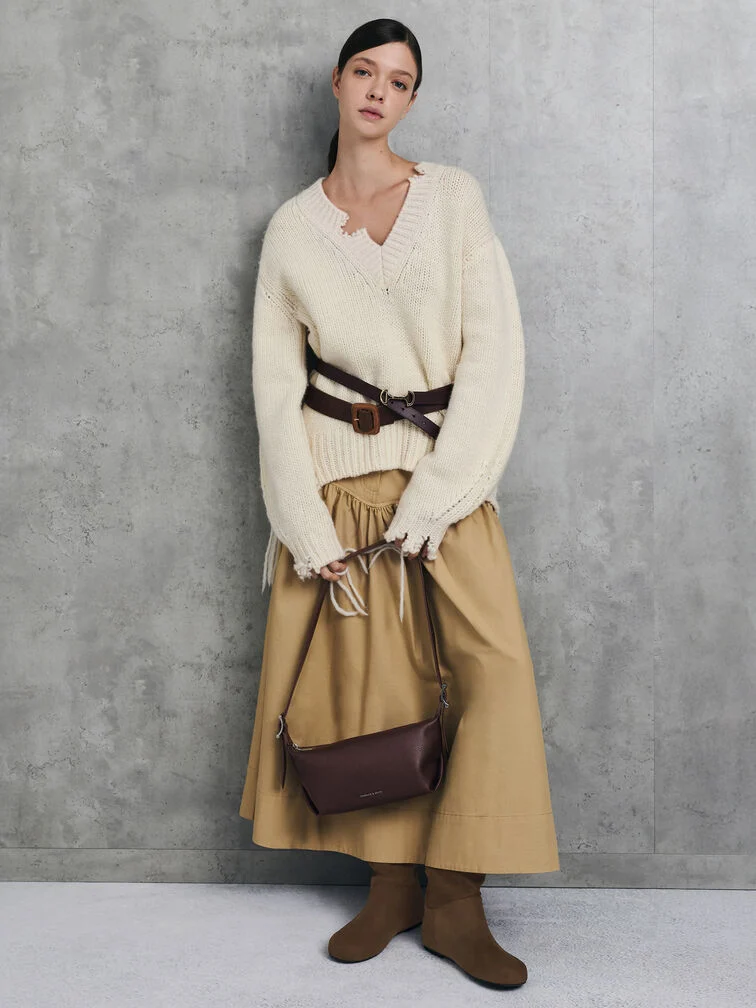Coordinated boots and bag refine an oversized sweater and long skirt ensemble for an elevated everyday look.