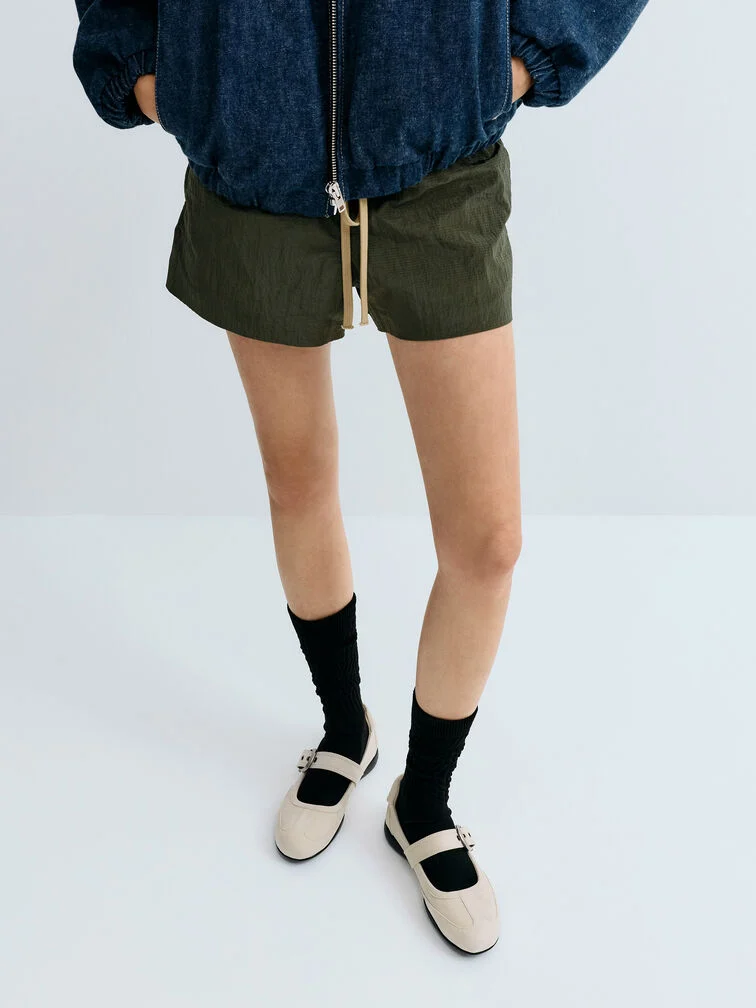 Mary Jane sneakers styled with black socks and casual shorts, for a sporty-chic look.