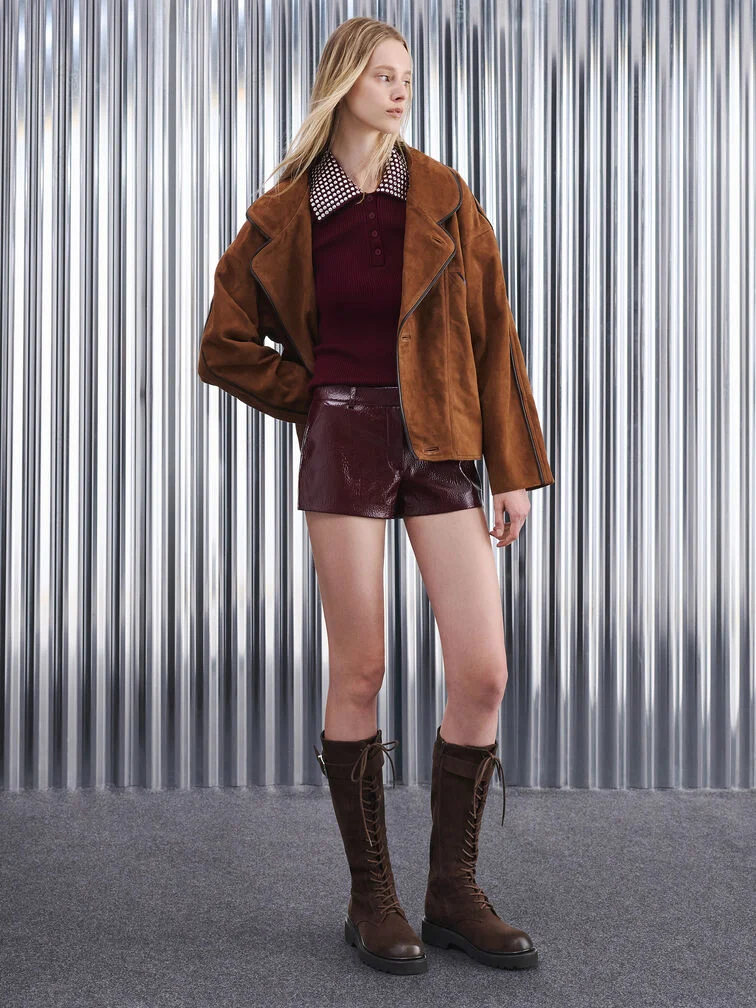Dark brown knee-high boots complement a rich burgundy outfit.