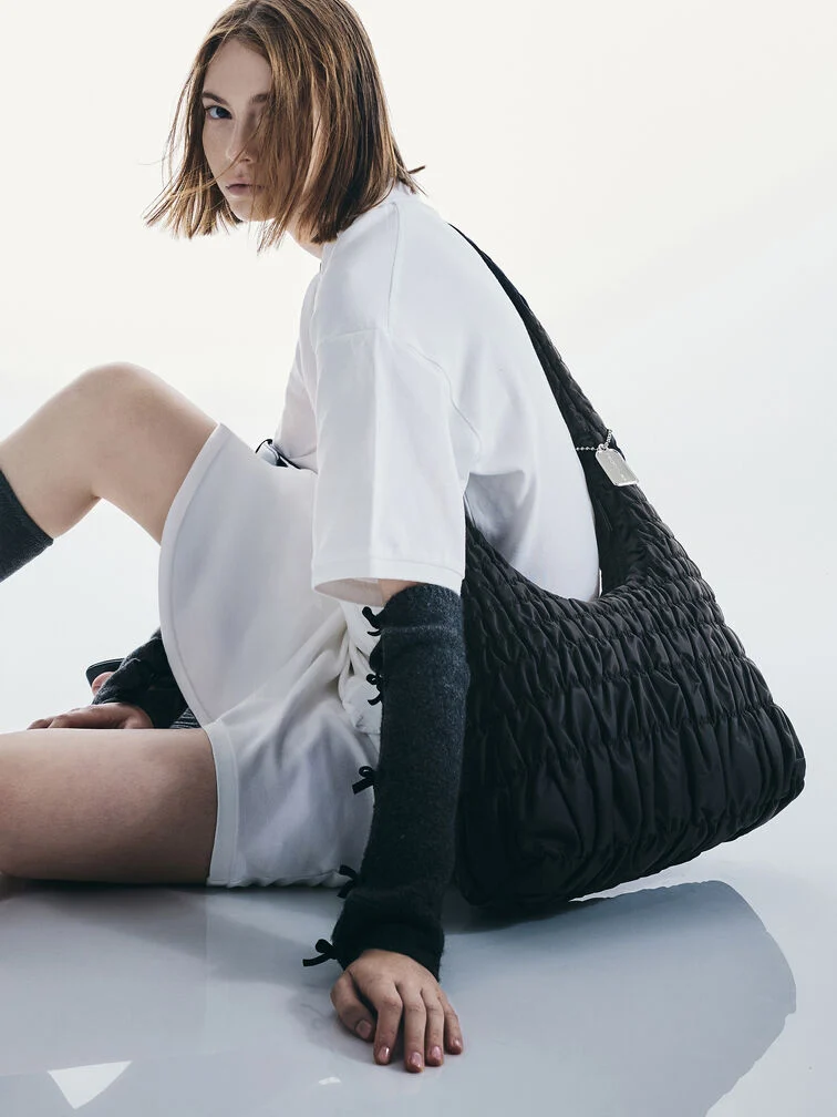 Black slouchy crossbody bag with a long strap and ruched finish.