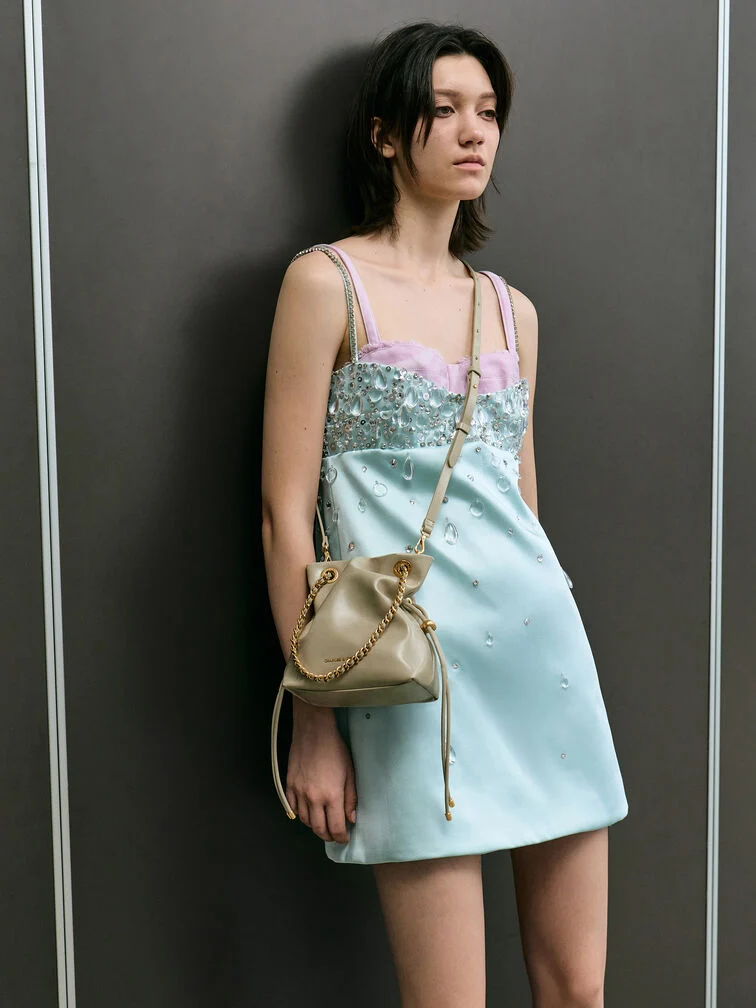 Pale olive slouchy crossbody bag with drawstring detailing, a compact solution for lighter days.