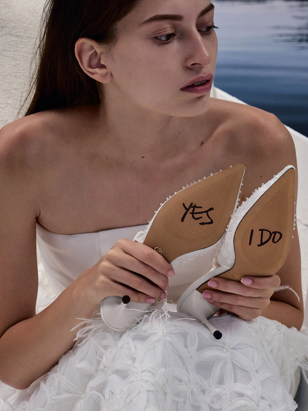 Bride holding shoes with “Yes I Do” written on the soles