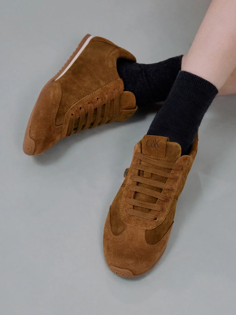 Low-profile brown suede sneakers with a slim silhouette.
