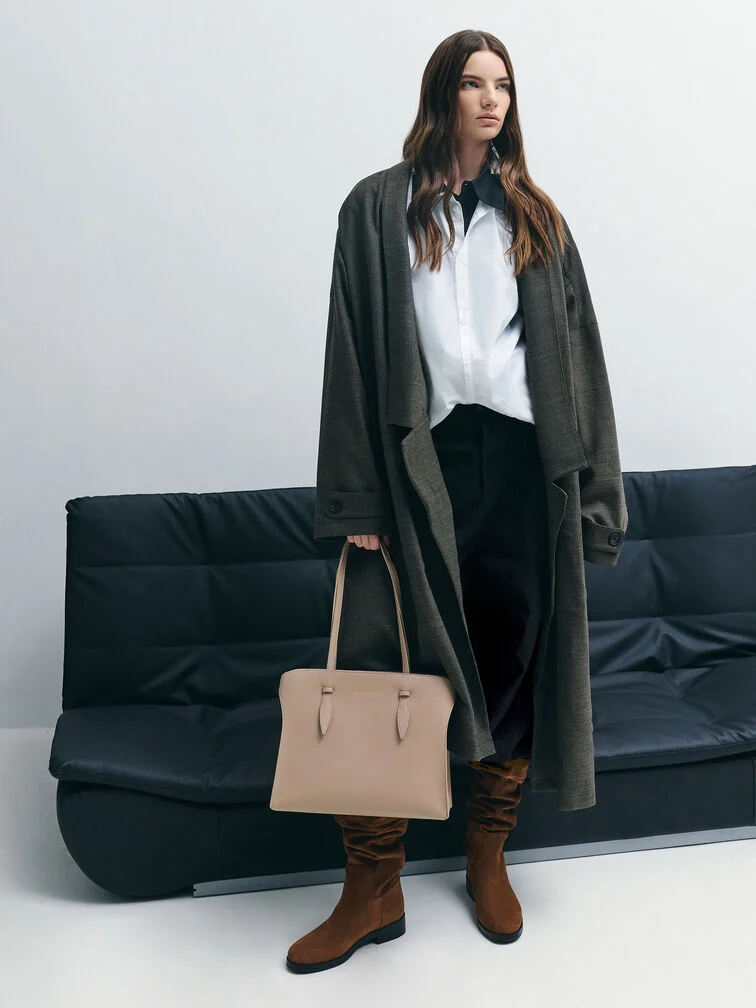 A smart-casual look featuring a button-down shirt, tailored pants, brown boots, relaxed outerwear and a taupe structured tote bag.